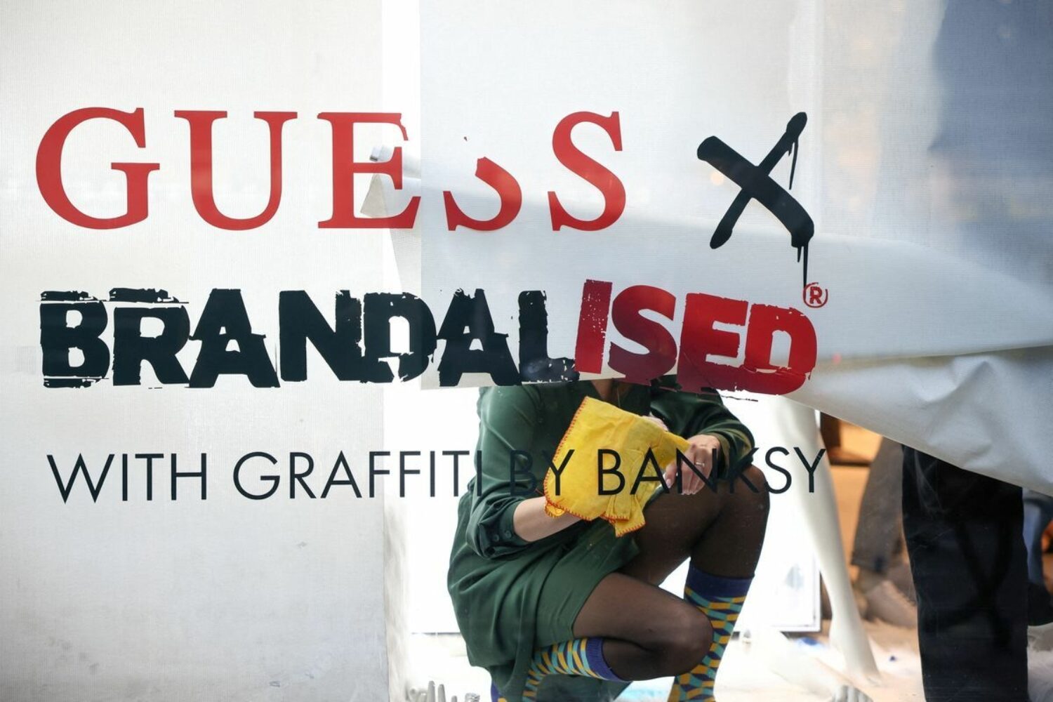 Employees remove lettering from a window display inside the flagship Guess store